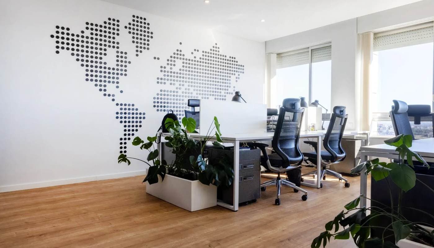 Open space de Reis & Pellicano avec une carte du monde en points au mur, des bureaux et de la lumière naturelle